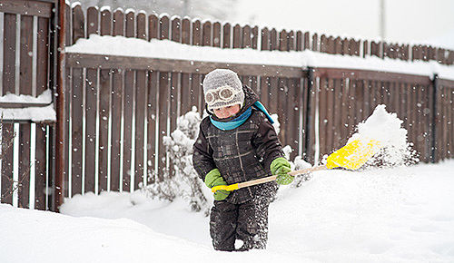 Ein kleines Kind versucht Schnee zu schaufeln. Noch sieht es wild entschlossen aus.